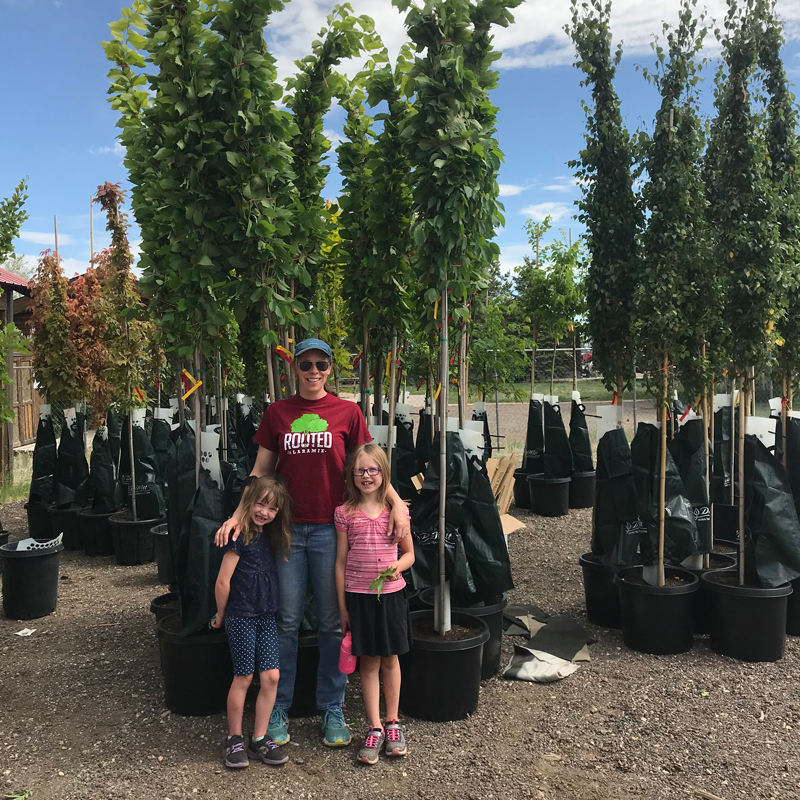 Executive direction Hilery Lindmier and her children pose in front of the 2020 planting trees that arrived in Laramie.